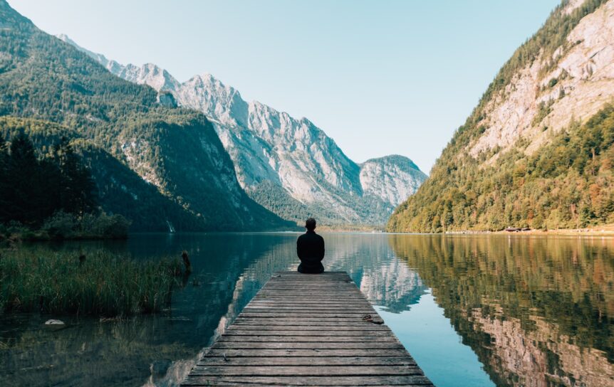 A man sitting in front of a lake relaxing, hosted by Wellin5.