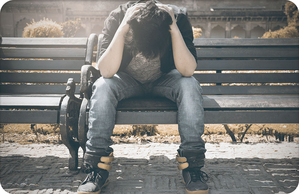 Man on bench, holding head in hands