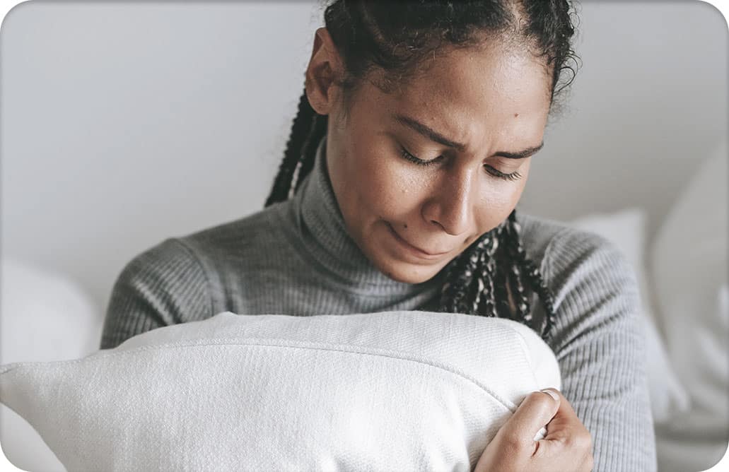 woman crying and holding pillow